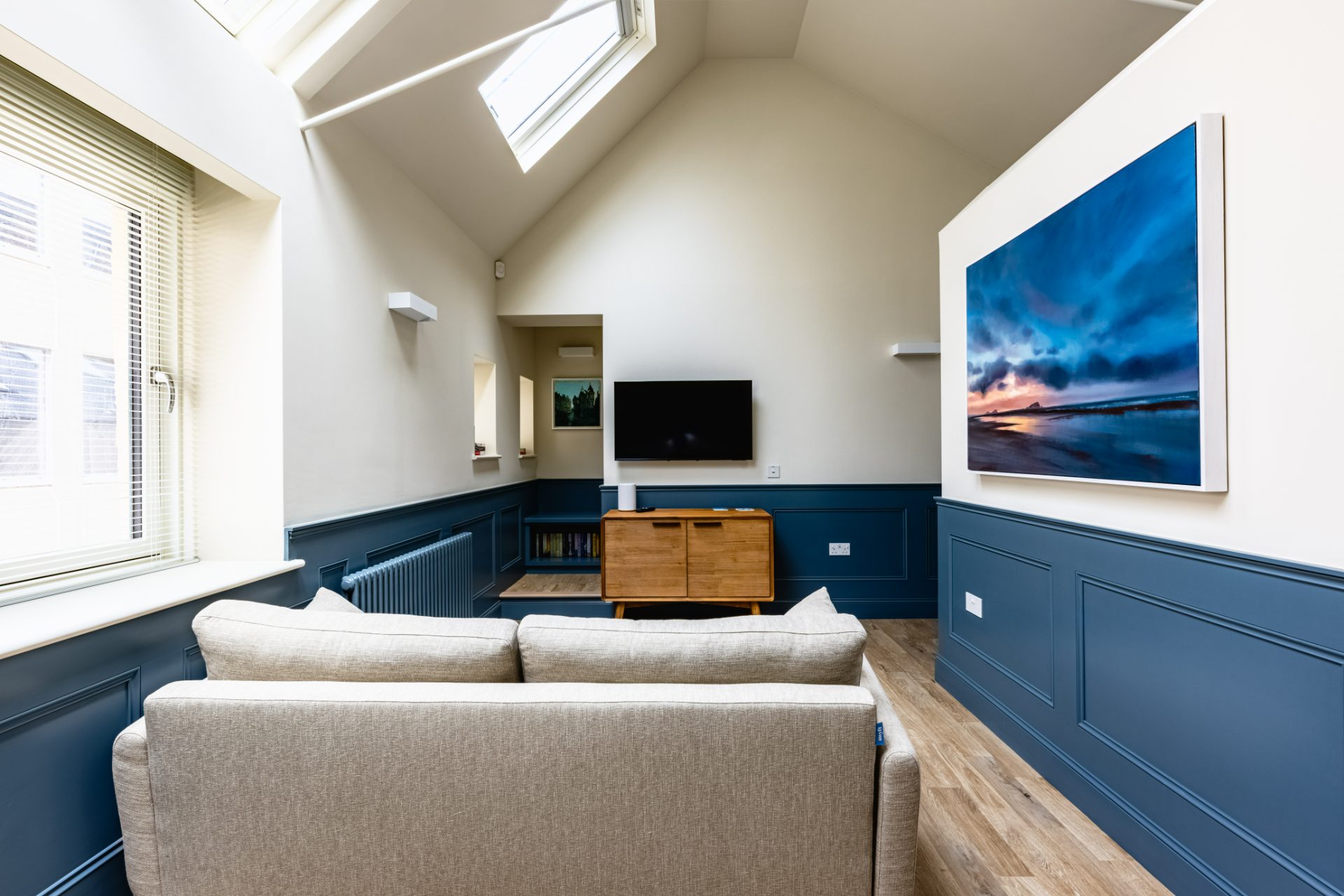The Hayloft — vaulted ceiling and rooflight with panelled walls and a Scottish seascape